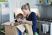 Mother and son unloading produce from box in kitchen