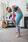 Woman practicing yoga at TV in living room