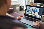 Woman with laptop video chatting with doctors from sofa