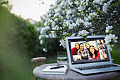 Happy friends video chatting on laptop screen in garden
