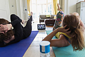 Mother and daughter taking online yoga class at home