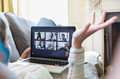 Young friends video chatting on laptop screen on sofa