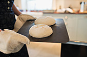 Close up woman with homemade bread dough on tray in kitchen