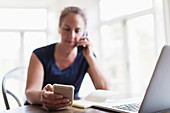 Woman talking on telephone and using smart phone at home