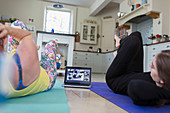 Mother and daughter taking online exercise class with laptop