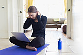 Teenage girl practicing yoga online with laptop