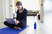 Teenage girl taking online yoga class with laptop