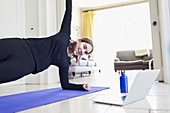 Teenage girl practicing yoga online at laptop at home