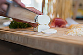 Close up knife cutting into fresh mozzarella cheese