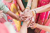 Indian women in bracelets joining hands in huddle