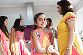 Portrait happy Indian girl in sari with women in kitchen