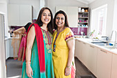 Happy Indian sisters in traditional saris in kitchen