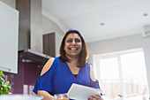 Portrait happy woman using digital tablet in kitchen