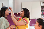 Indian woman placing bind on forehead of sister