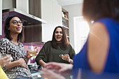 Women talking and drinking tea in kitchen