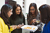 Indian women with tea and food in kitchen