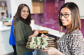 Portrait smiling Indian woman with tray of kebabs in kitchen