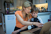 Mother helping son with homework at laptop