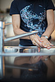 Woman washing hands at kitchen sink