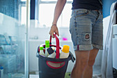 Woman with bucket of cleaners cleaning bathroom