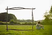 Branch frame over woman relaxing in summer grass field