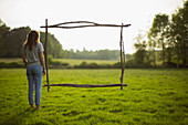 Branch frame over woman standing in idyllic grass field