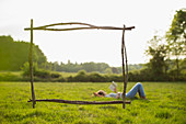 Branch frame over woman reading book in idyllic grass field