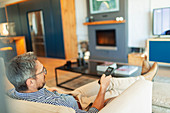 Man relaxing, watching TV in living room