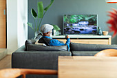 Man watching TV on living room sofa