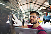 Focused male mechanic using digital tablet