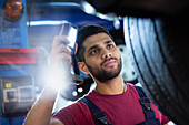 Mechanic with flashlight examining tire