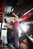 Male mechanics working under car