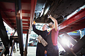 Male mechanics with flashlight working under car