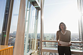 Businesswoman at sunny highrise office window