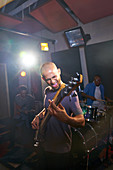 Male musician playing guitar in recording studio