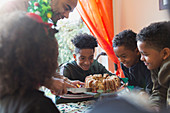 Father serving Christmas cake to eager sons