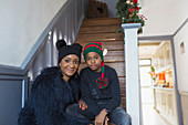 Mother and son in Christmas hats on stairs at home