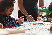 Girl decorating Christmas cookies with family