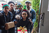 Family delivering Christmas gifts at front door