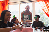 Father serving Christmas cake to family at table