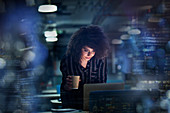 Businesswoman working late at laptop with coffee
