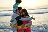 Happy family hugging on ocean beach