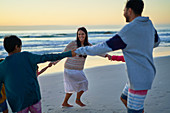 Happy family holding hands in circle on beach