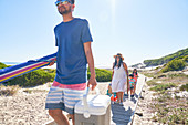 Family carrying beach equipment on sunny boardwalk