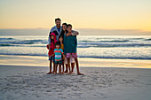 Portrait happy family on ocean beach at sunset