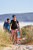 Happy boy carrying folding chair on beach