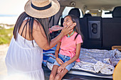 Mother applying sunscreen to daughter