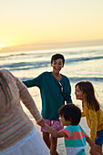 Happy family playing on beach at sunset