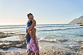 Father and son walking on sunny ocean beach