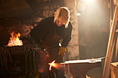 Female blacksmith forging steel in workshop